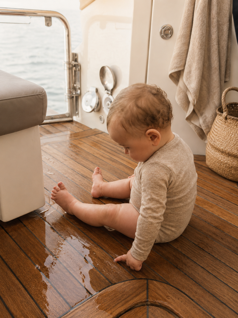 Baby spielt im Merinobody mit Wasser